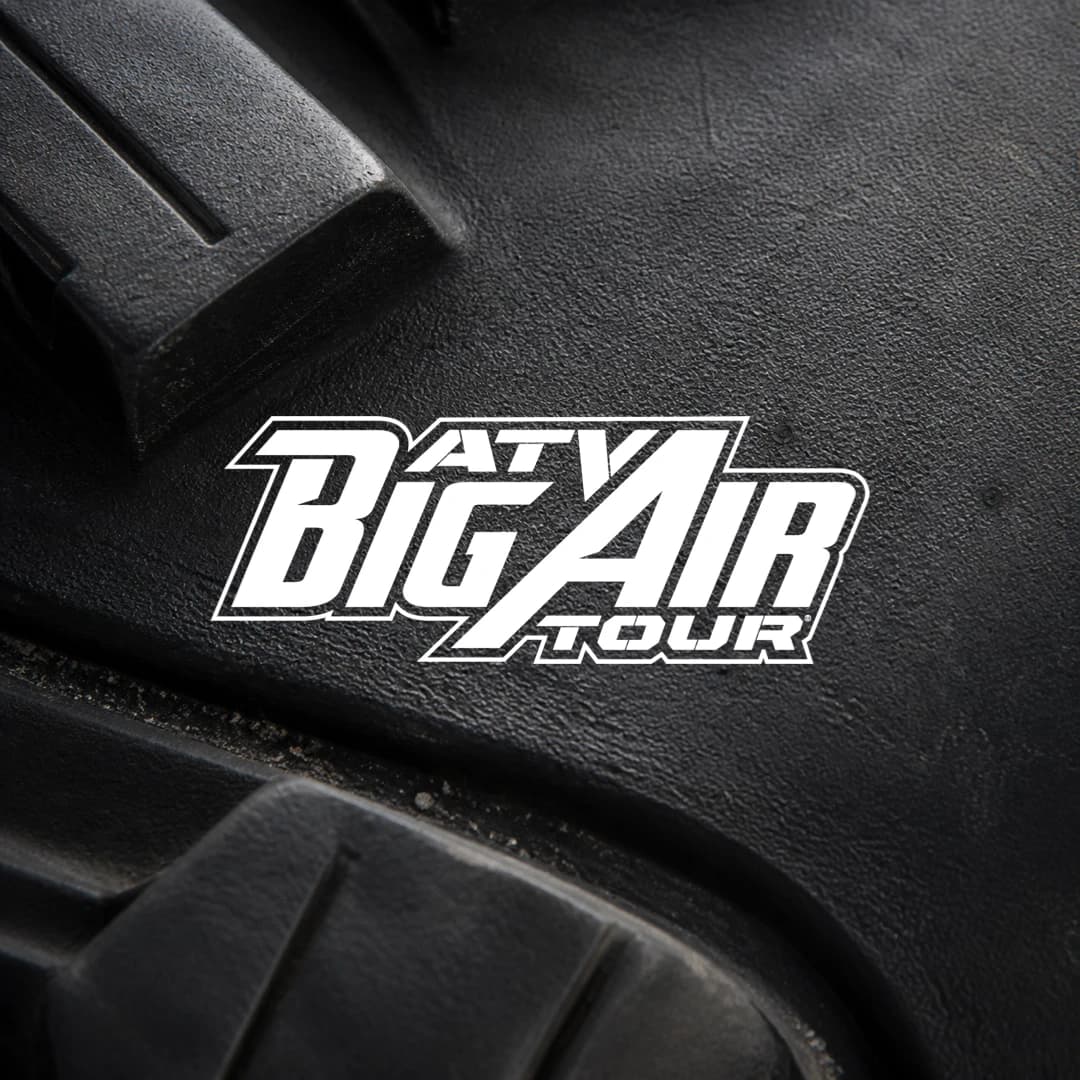 ATV Big Air Tour logo on a close-up black ATV tire texture.