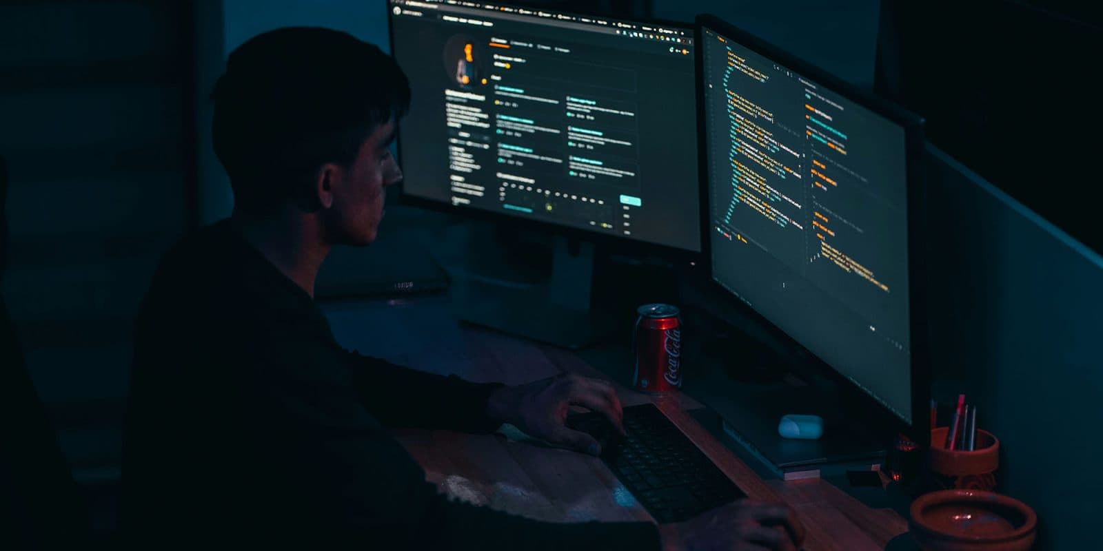 Apple blocks web certificates that could be used by scammers, but Mac vulnerability remains | Photo shows a man working on code in a darkened room