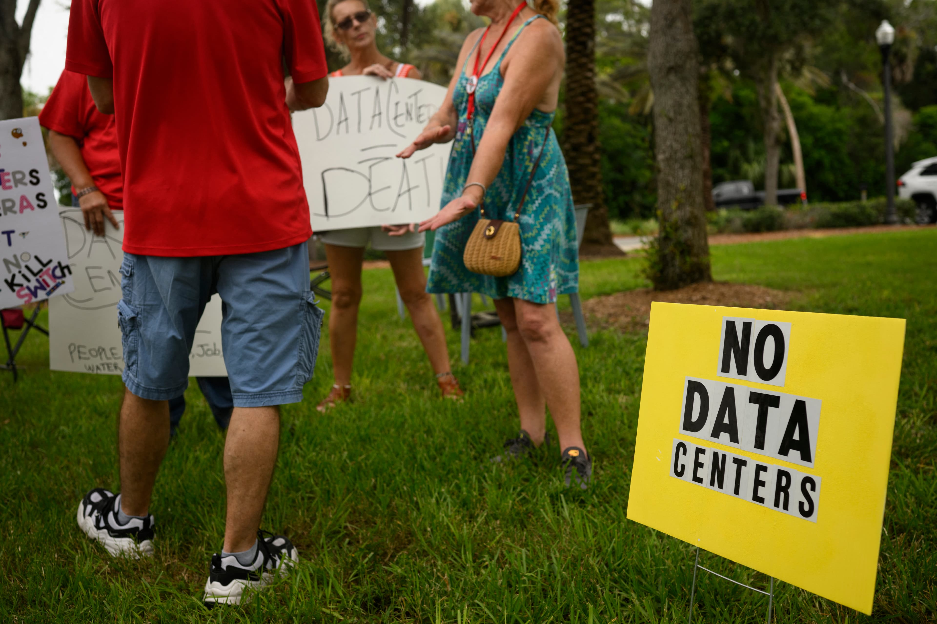 People hold signs during a nationwide protest against AI data center expansion outside Peace Hall in New Port Richey, Florida.